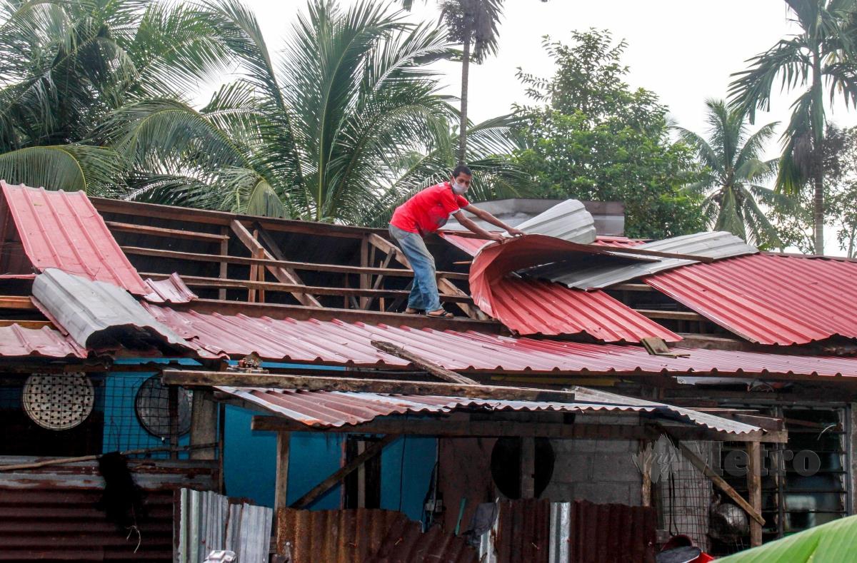 Penduduk kampung membaiki atap yang diterbangkan ribut dalam kejadian berlaku lewat petang semalam di Kampung Nara, hari ini. FOTO BERNAMA