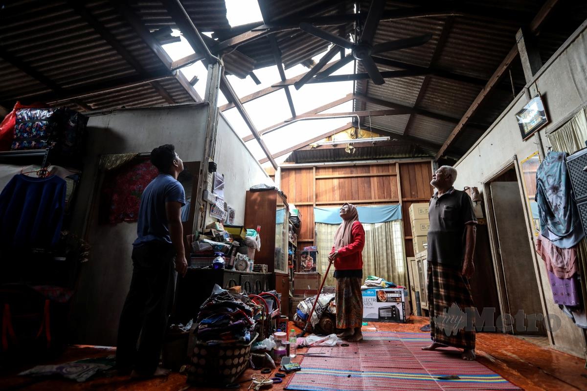Kamaruddin Jusoh, 69 (kanan) bersama isterinya Zaharah Ibrahim, 62, melihat bumbung rumah yang rosak dibadai ribut dalam kejadian  petang semalam di Kampung Teluk Ketapang, Seberang Takir. FOTO GHAZALI KORI