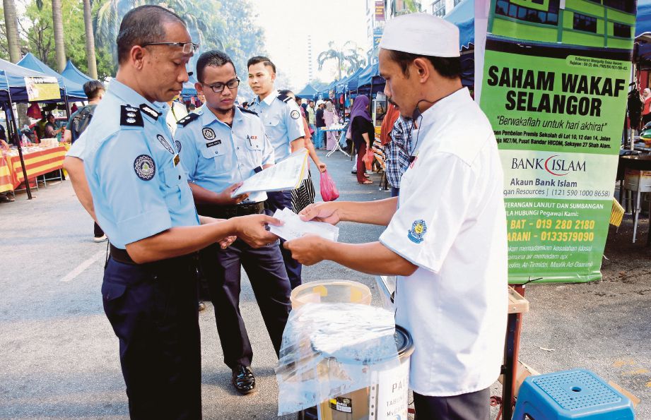 MAHDI  (kiri) membuat pemeriksaan terhadap individu yang disyaki meminta derma tanpa kebenaran  di Bazar Ramadan Puchong Prima. 