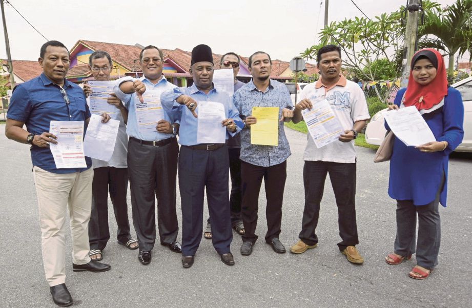 ABDUL  Talib (tiga dari kiri) bersama  penduduk setempat menunjukkan notis cukai taksiran Majlis Daerah Kuala Langat pada sidang media di Taman Pahlawan.