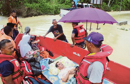  Anggota pasukan penyelamat dan penduduk kampung membantu Alias Wahab, 77, yang menghidap angin ahmar untuk dipindahkan ke pusat pemindahan mangsa banjir di Balai Raya Kampung Gadek Dalam. 