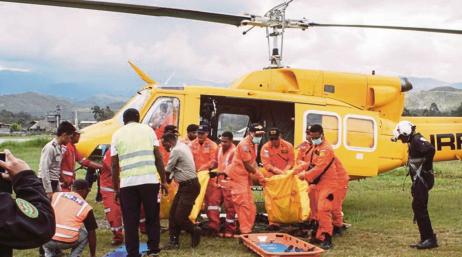 PASUKAN mencari dan menyelamat membawa keluar mayat mangsa pesawat terhempas dari helikopter yang tiba di lapangan terbang Wamena di Papua semalam. - Agensi