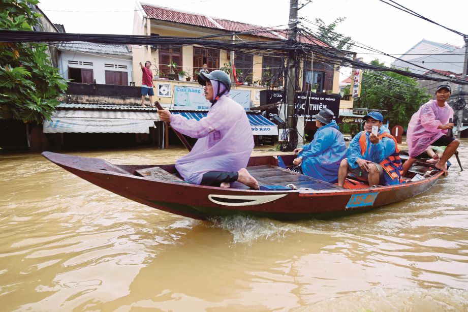 PENDUDUK menaiki bot di bandar Hoi An, tengah Vietnam yang ditenggelami air semalam. - Reuters