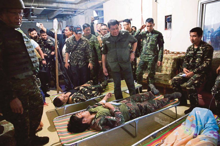 DUTERTE (tengah) melawat anggota tentera yang cedera ketika melawat kem tentera di bandar Marawi, kelmarin.  - EPA 