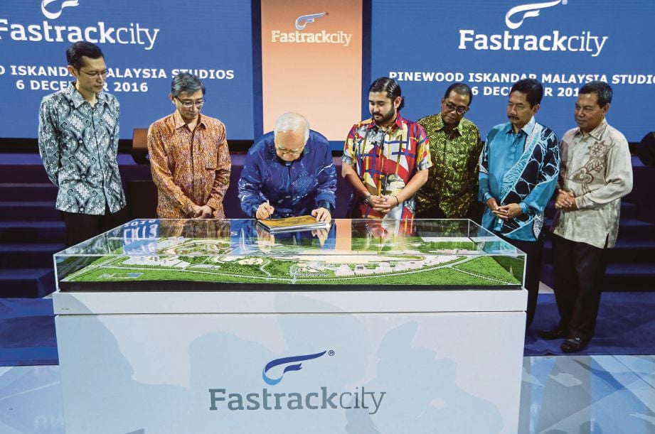 Tunku Ismail (empat dari kanan)   menyaksikan  Najib  menandatangani plak pada  majlis pelancaran reka bentuk pembangunan Fastrack City di Pinewood  Iskandar Malaysia Studios, semalam.