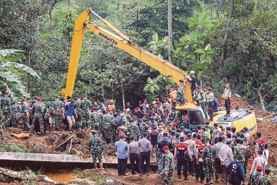 Pasukan penyelamat berusaha mencari mangsa yang terperangkap di bawah tanah runtuh di Cijeruk, Jawa Barat, semalam. - EPA