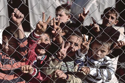 SEKUMPULAN kanak-kanak pelarian Kurdis Syria menunjukkan tanda ‘V’ di sebalik pagar di kem pelarian di bandar Suruc, wilayah Sanliufa, semalam.  Mereka adalah antara ribuan penduduk Kobane di utara Syria yang lari menyelamatkan diri daripada serangan militan IS.