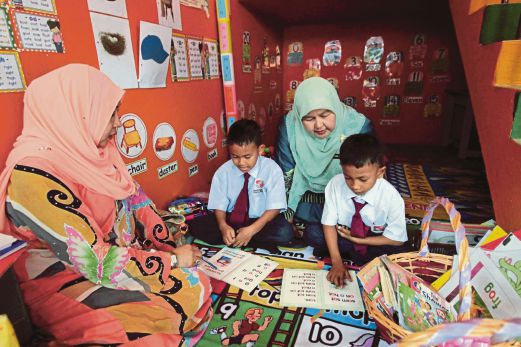  GURU mengajar dua anak murid pada Program Anak Angkat di sudut bawah tangga  SK Kamil 1, Pasir Puteh.