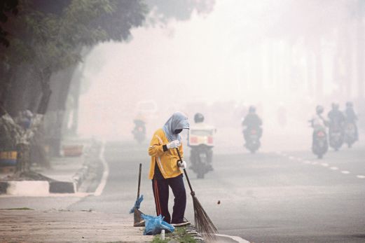 SEORANG pekerja menyapu sampah di tepi jalan di Pekanbaru di wilayah Riau, semalam.