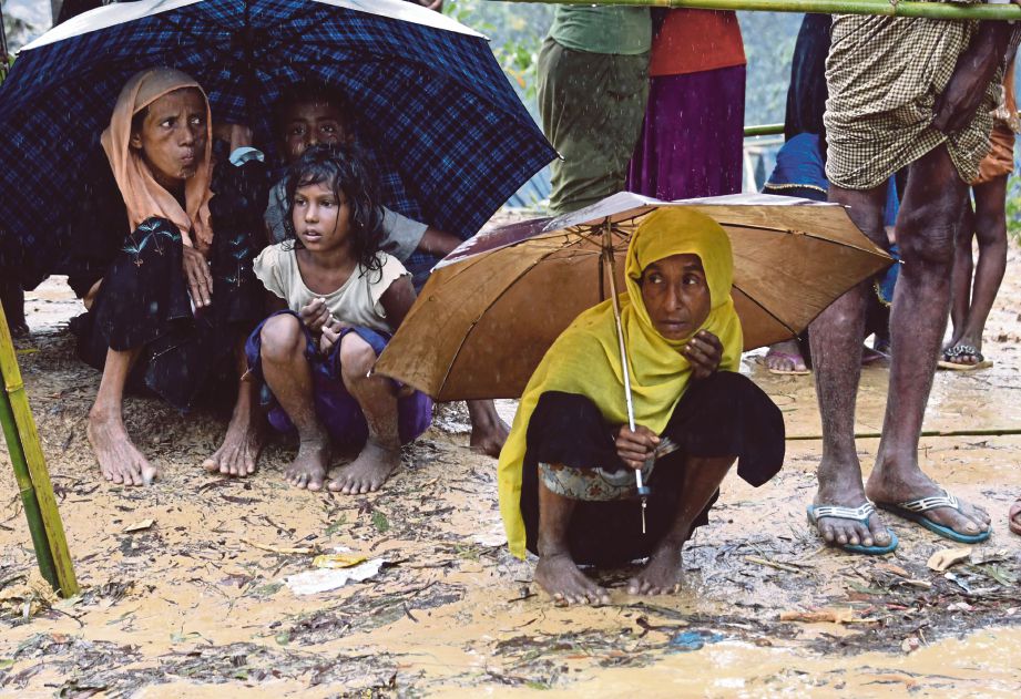 PELARIAN Rohingya berteduh dalam hujan di kem pelarian Balukhali, Bangladesh. -  AFP  