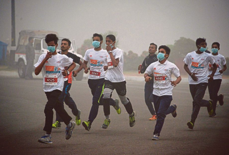 KANAK-KANAK sekolah berlari dalam asap tebal ketika mengambil bahagian dalam acara larian 10 kilometer di New Delhi, semalam.  - AFP