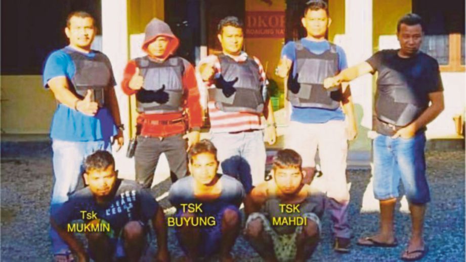 ANGGOTA polis bergambar bersama tiga suspek (duduk) yang ditangkap kerana disyaki membunuh tiga keluarga mereka di Madina, Sumatera Utara baru-baru ini. - Tribunnews
