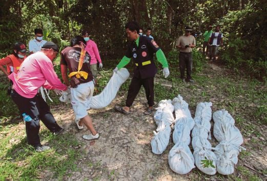 PETUGAS pasukan keselamatan Thai mengangkat mayat yang digalikan dari sebuah kubur besar di kebun getah di  Songkhla, semalam.