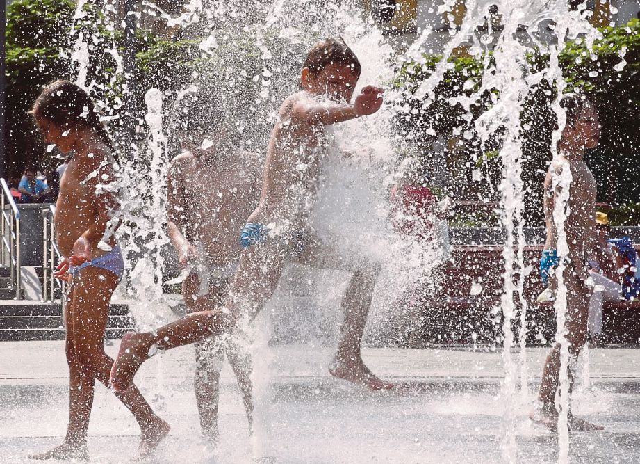 KANAK-KANAK bermain di air pancur ketika cuaca panas di Kiev, Ukraine, kelmarin. - Agensi  