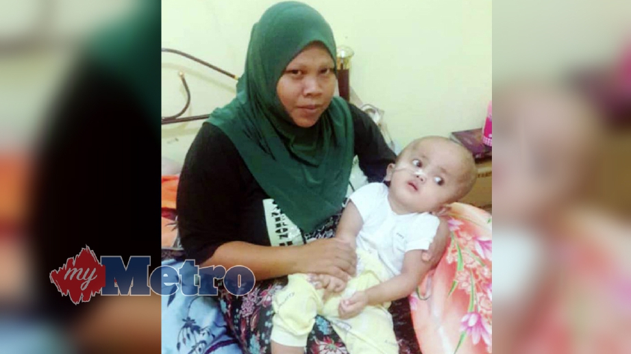 NURUL Lia Hamat Hassan memangku anaknya, Nur Emylyiana Atesyah A Halim atau dipanggil  Echa yang menghidap 'congenital hydrocephalus' di rumahnya di Kampung Sangkabok, Menumbok, Kuala Penyu. FOTO Ihsan  Nurul Lia Hamat Hassan
