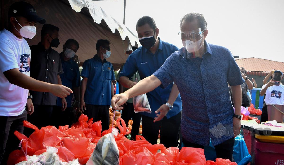 Perdana Menteri Tan Sri Muhyiddin Yassin (kanan) melihat barangan sumbangan yang akan diagihkan kepada penduduk pada majlis Sumbangan Makanan Basah dan Bakul Prihatin kepada Penghulu-Penghulu di Kompleks Penghulu Mukim Sungai Raya, hari ini. FOTO BERNAMA