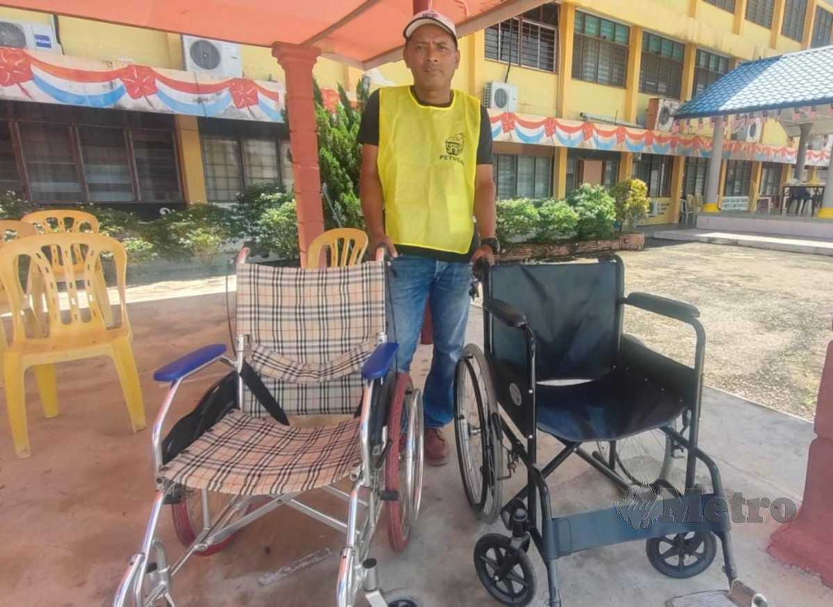 Syuwardy Ismail, 49, bersama kerusi roda milik ibu dan bapanya yang dipinjamkan untuk kegunaan pengundi di pusat mengundi Dewan Undangan Negeri (DUN) Gual Periok di SMK Gual Periok, di sini, hari ini.FOTO SYAHERAH MUSTAFA
