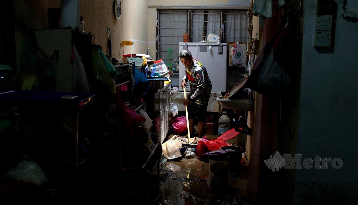 Mangsa banjir kilat, Faizal Shaiyuddin, 46, membersihkan rumah ibu bapanya selepas ditenggelami air ekoran hujan lebat di Taman Seri Kota Fasa Dua, hari ini. FOTO BERNAMA