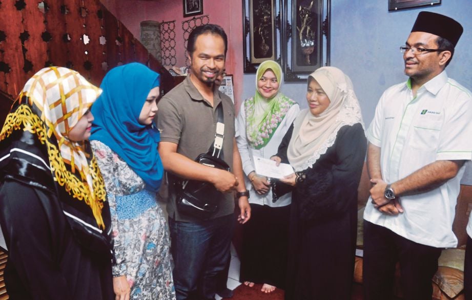 ROSNI (dua dari kanan) menyampaikan sumbangan kepada Muhammad Saiful Iskandar.