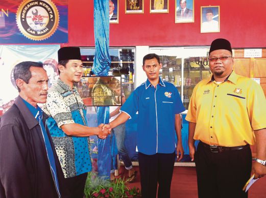 KHALID (dua dari kiri) bersalaman dengan Ramlie ketika majlis perasmian Pusat Servis Kenderaan RSK Enterprise di Kampung Melayu Majidee.