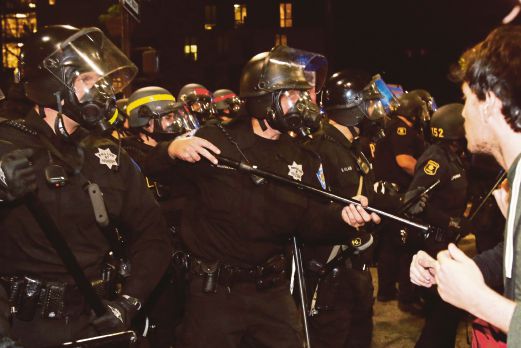 ANGGOTA polis di Berkeley, California cuba menghalang penunjuk perasaan selepas mereka mula bertindak ganas, semalam.  