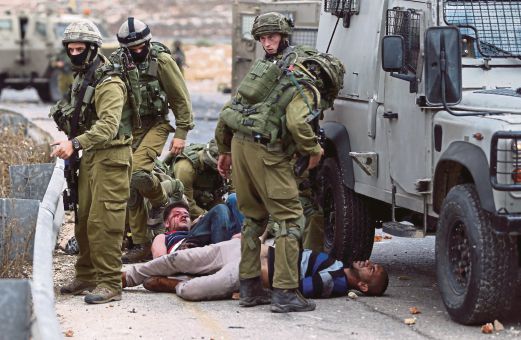 TENTERA Israel menahan penunjuk perasaan Palestin yang cedera dalam pertempuran berhampiran penempatan Yahudi Bet El di Ramallah, Tebing Barat, semalam.  