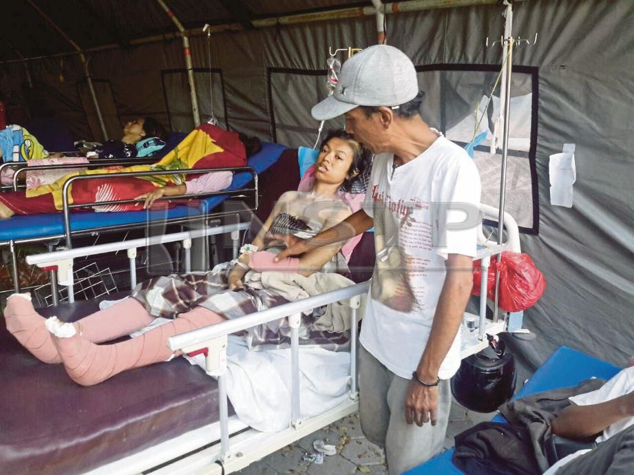 EMRAN  menemani isterinya, Nyonya  yang dirawat di kawasan parkir Hospital Undata Palu yang dijadikan hospital medan.