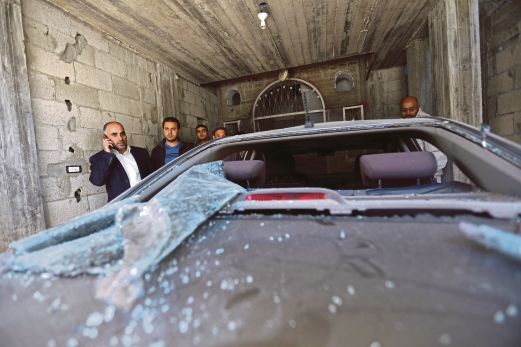 Seorang pemimpin kanan Fatah di Gaza, Fayez Abu Eitta (kiri) memeriksa kerosakan terhadap keretanya di tempat letak kenderaan rumahnya di Beit Lahya, utara Semenanjung Gaza.