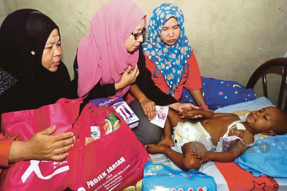 ZURAINI (tengah) ketika melawat dan menyerahkan bantuan kepada Muhammad Muazzudin Mohd Hayat, 3, yang menghidap kanser neuroblastoma tahap empat di rumahnya di Kampung Telok Nibong, Jitra. 