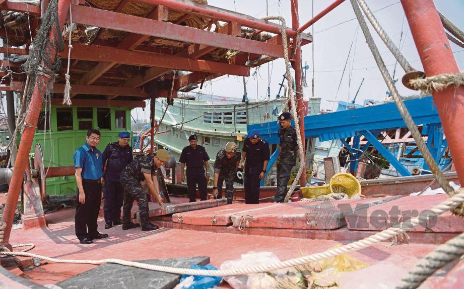  FISOL  (tiga dari kanan) membuka tempat penyimpanan ikan dalam bot nelayan Vietnam yang ditahan dalam Operasi Gelora Khas, semalam.