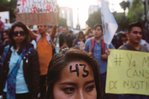 SEORANG wanita dengan nombor 43 dicat pada dahinya, merujuk kepada jumlah pelajar yang hilang, menyertai tunjuk perasaan di Mexico City, semalam. 