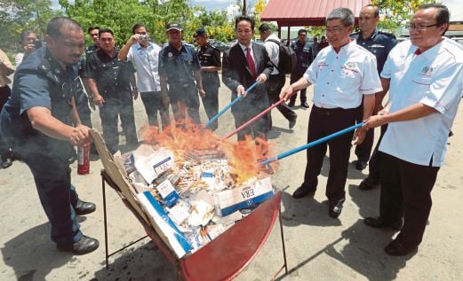   Matrang   (tiga dari kanan) membakar rokok rampasan pada pelancaran   Ops Pacak 2015 peringkat Sabah,  kelmarin.