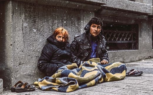 DUA pelarian Syria duduk di kaki lima ketika salji melanda Istanbul, semalam. 