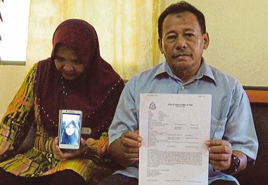 WAN Zainuddin dan isteri menunjukkan laporan polis dan gambar anaknya Wan Syazlin.