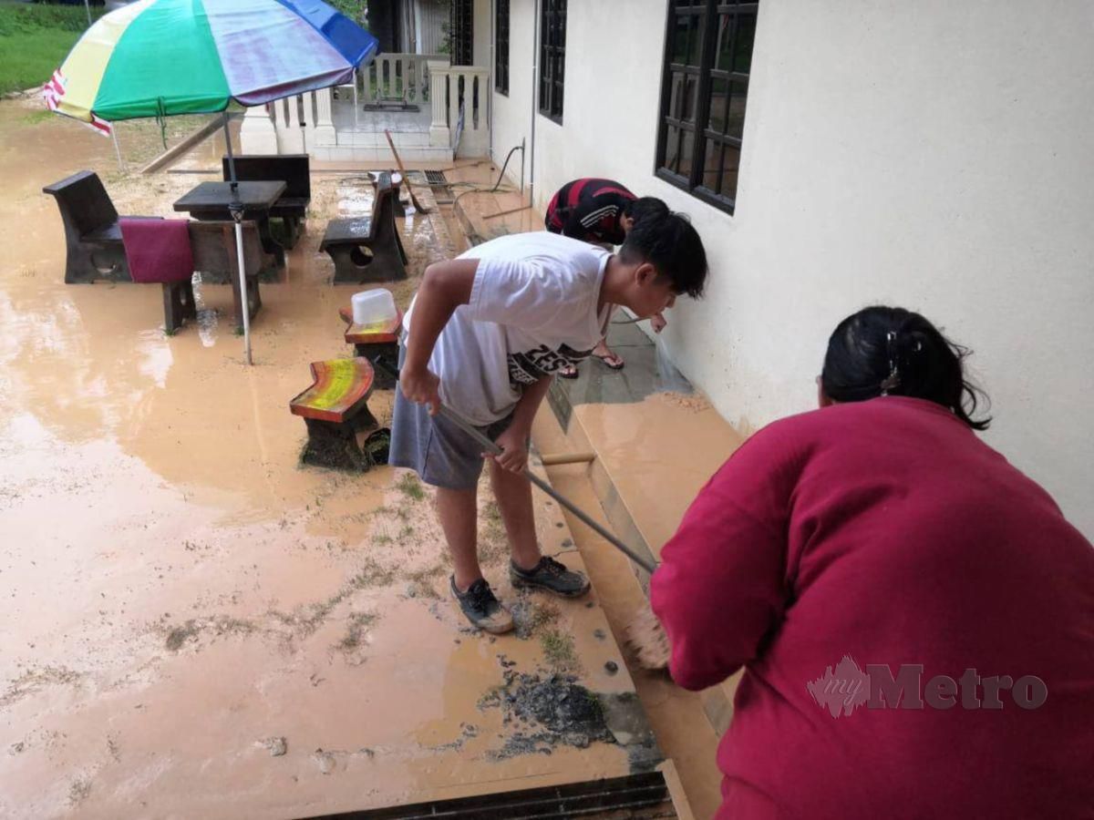 Penduduk Kampung Batu 5 Bangi, Semenyih membersihkan kawasan rumah yang dilanda banjir kilat semalam. FOTO Ihsan penduduk