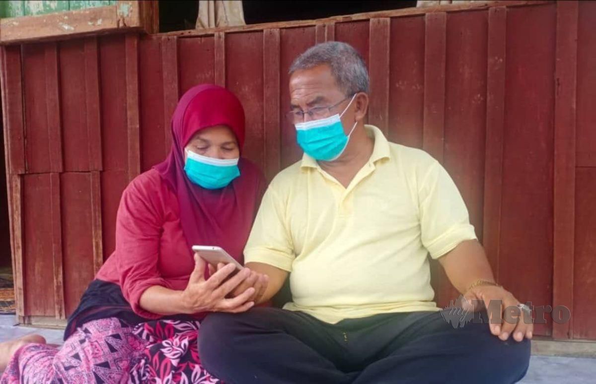 Ibrahim Ali, 68, dan Bedah Rusi, 68 melihat gambar cucunya melalui telefon bimbitnya di kediaman di Felda Kota Gelanggi Dua. FOTO ROSELAN AB MALEK