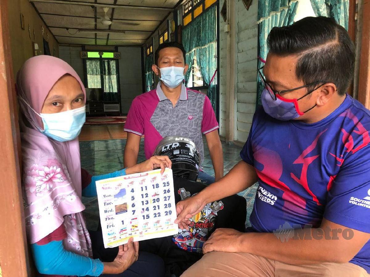 Rafidah Astopa, 51, kakak Allahyarham Hairizam, 40, menunjukkan kalender milik Allahyarham kepada Pengerak Southern Volunteers Simpang Renggam, Zamrie Baharuddin (kanan) di Kampung Tengah Renggam, Kluang Johor. FOTO MOHAMAD FAHD RAHMAT