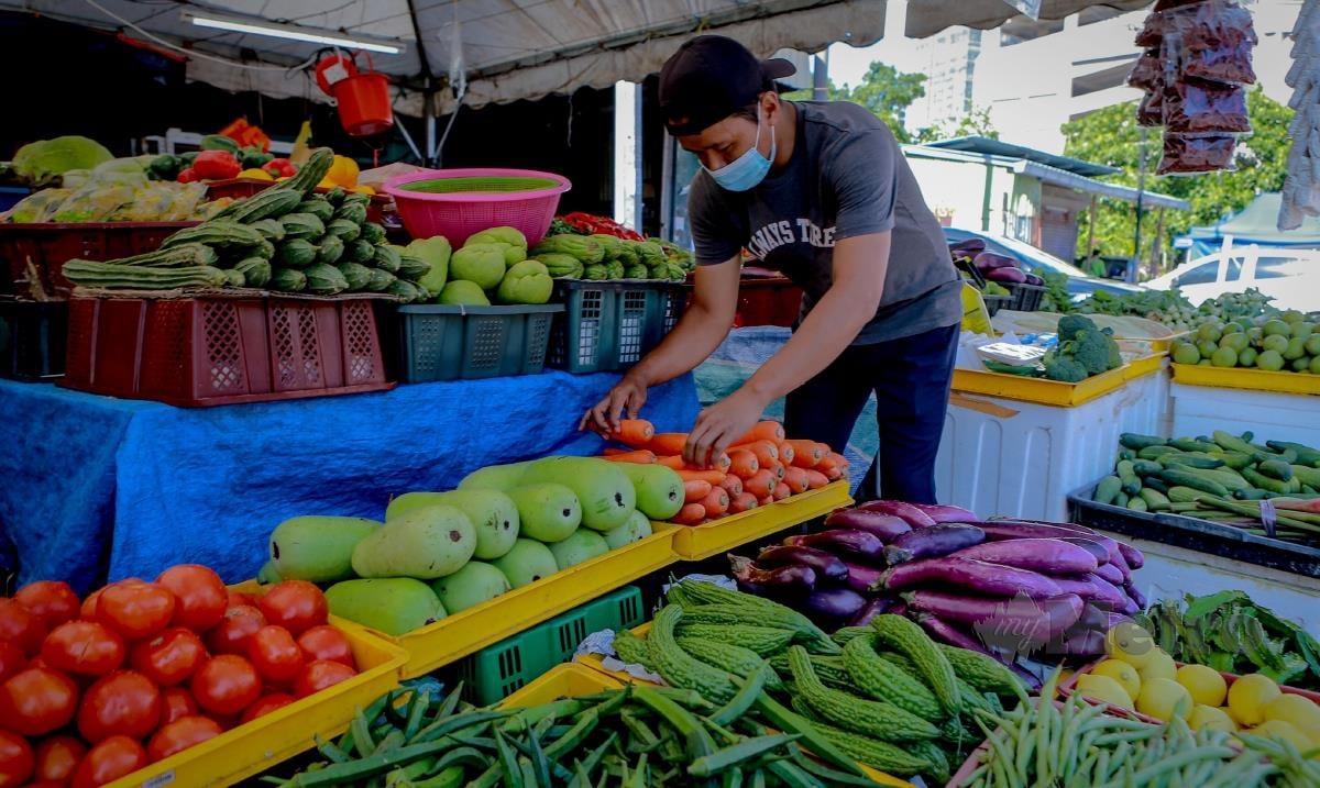 Seorang peniaga menyusun pelbagai jenis sayur-sayuran di gerainya di Jalan Raja Alang. FOTO ASYRAF HAMZAH