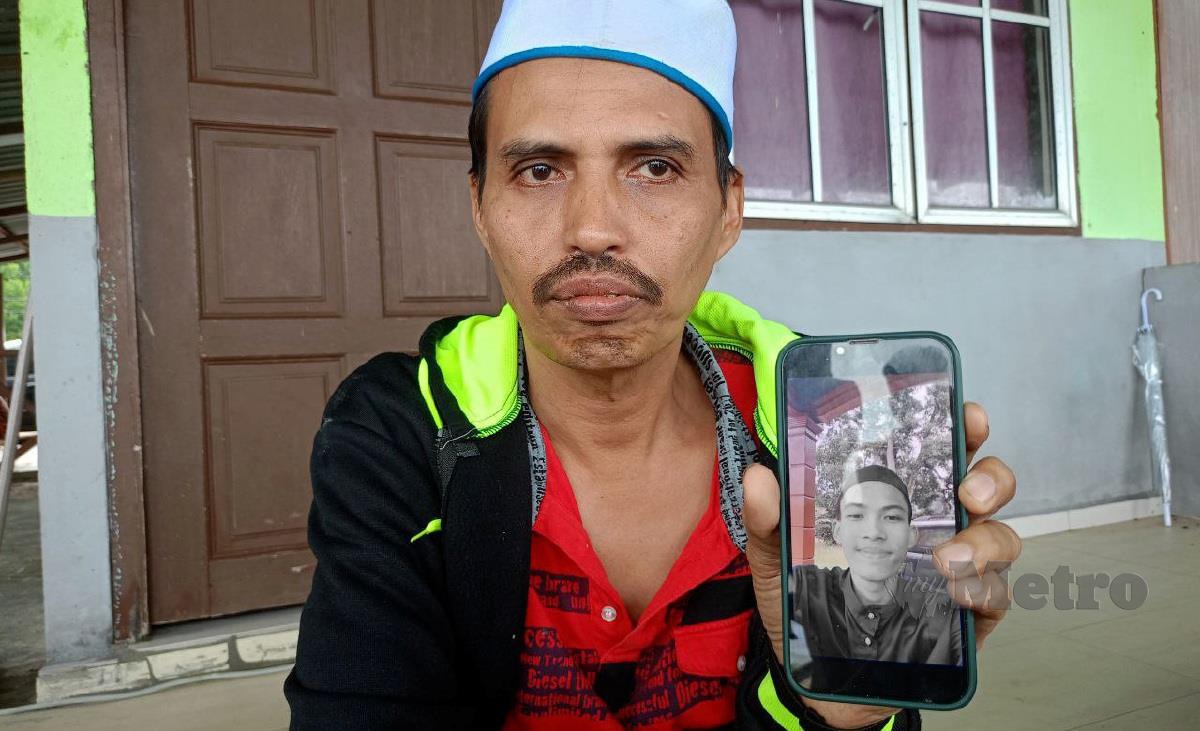 Mohd Fadzli menunjukkan gambar anaknya, Muhammad Fahmi Hafizi yang dilaporkan hilang selepas ditarik ombak kuat di Pantai Teluk Senangin, semalam. FOTO MUHAMAD LOKMAN KHAIRI