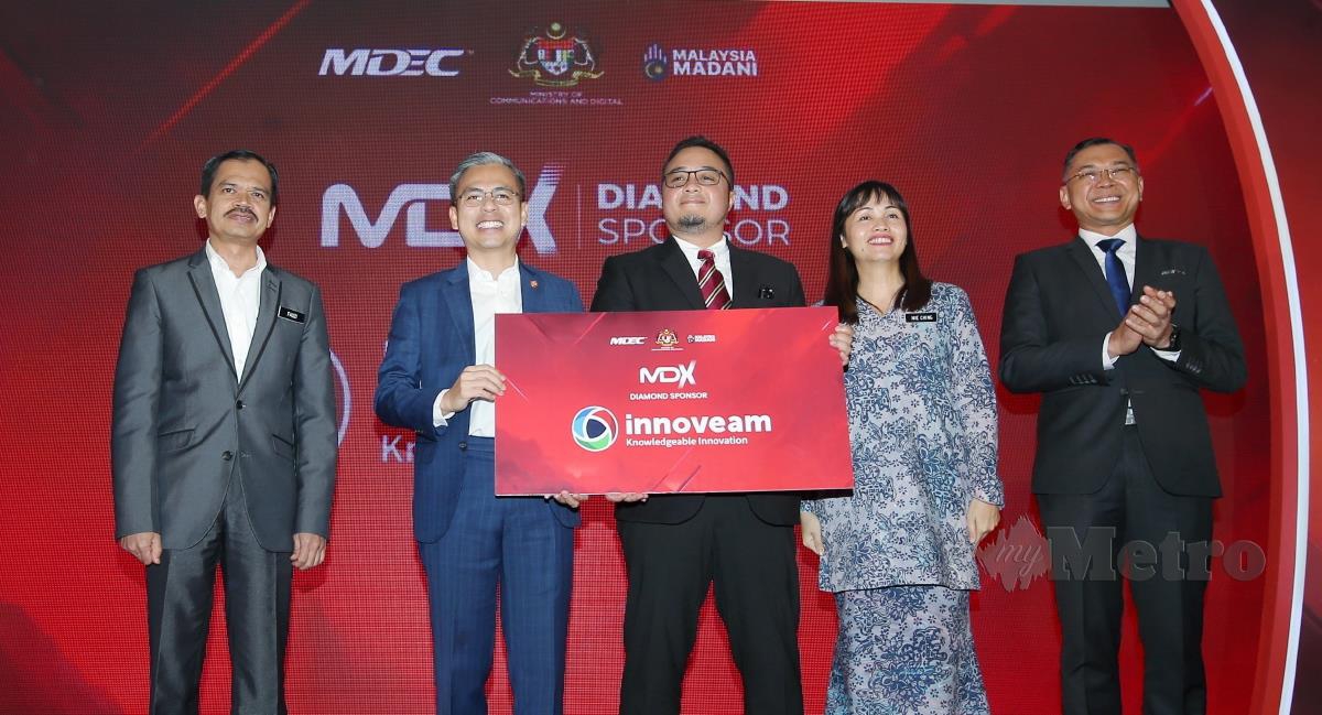 Pengarah Urusan Innoveam, Zamir Rashid (tengah) menyampaikan replika penajaan kepada Menteri Komunikasi Dan Digital, Fahmi Fadzil (dua dari kiri) di Majlis Pelancaran Malaysia Digital Expo (MDX) 2023 yang diadakan di One World Hotel. FOTO EIZAIRI SHAMSUDIN