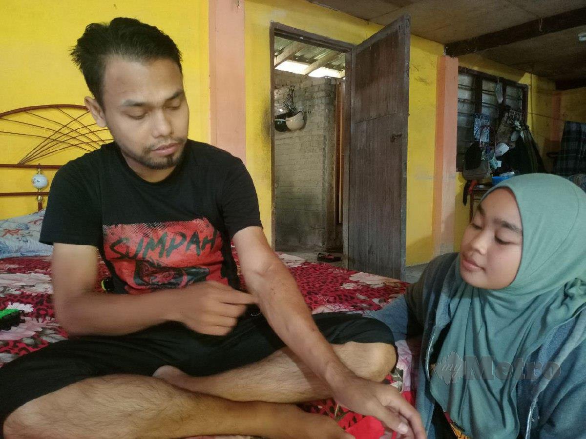 Mohd Hamdan Mohd Daud, 28, menunjukkan tapak fistula untuk rawatan dialilis di lengannya sambil diperhatikan isteri, Fatihah Mohd Rozali, 24, ketika ditemui di Kampung Teluk Jering. FOTO SITI ROHANA IDRIS