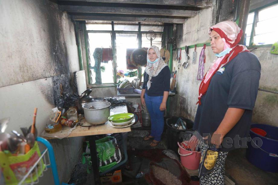 Nuraina Erieka Abdullah (kiri) bersama ibunya Nur Zalina Mohd Fauzi melihat kesan kebakaran rumah mereka di flat Taman Anggerik Desa Jalan Beserah. FOTO MOHD RAFI MAMAT