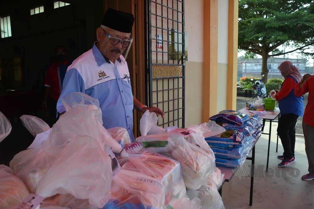 Md Rawi menyusun bahan makanan untuk diagihkan kepada anggota komuniti yang terkesan akibat pandemik COVID-19 di Dewan JAPERUN Tanjung Bidara, Masjid Tanah. FOTO Hassan Omar