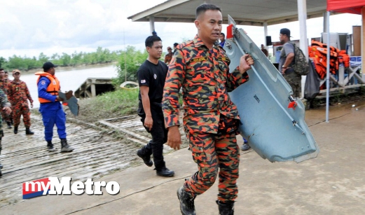 ANGGOTA Bomba dan Penyelamat menggangkat serpihan helikopter yang membawa rombongan kenamaan ketika dalam perjalanan pulang dari Betong ke Kuching di Jeti Lingga. FOTO Khairull Azry Bidin