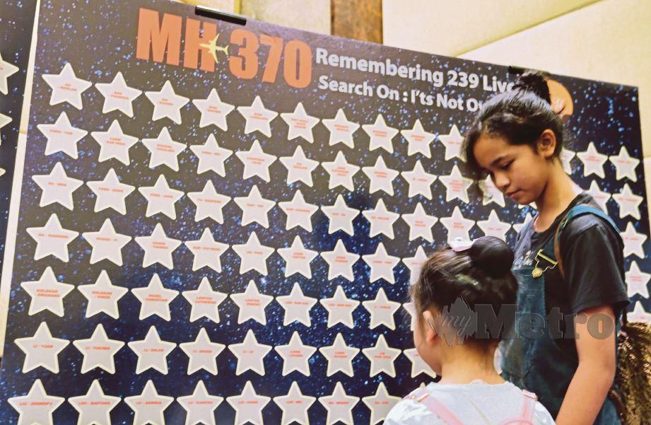 SEBAHAGIAN ahli keluarga yang hadir melihat senarai nama penumpang pesawat MH370 pada majlis memperingati di Putrajaya, kelmarin. 