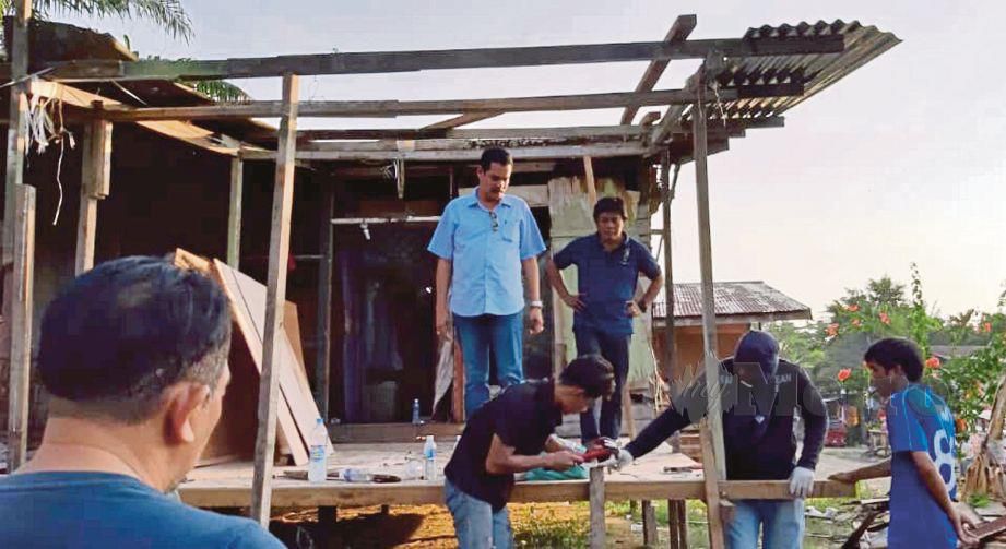 JAFFARI  (tengah) memantau kerja membaiki rumah Bilani. 