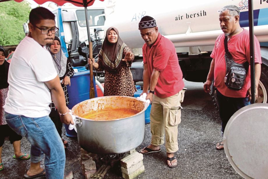 AHLI keluarga Rosli Abd Aziz bergotong-royong memasak untuk kenduri majlis pernikahan anak perempuan selepas mengambil bekalan air yang dibawa oleh lori tangki air SYABAS  di Pangsapuri Kos Rendah Taman Setia Balakong, Seri Kembangan, semalam. 