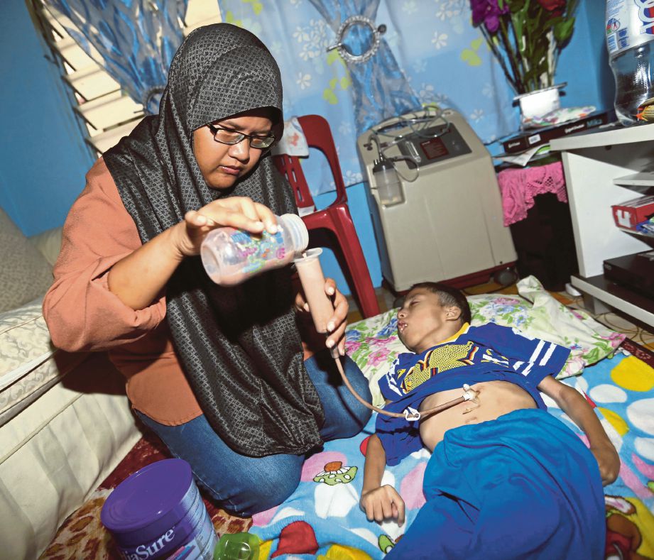 Norazifa memberikan susu melalui tiub ke perut anaknya, Muhammad Faiz Irfan yang memiliki lebih lapan kecacatan di rumahnya PPR Desa Mutiara, Johor bahru.