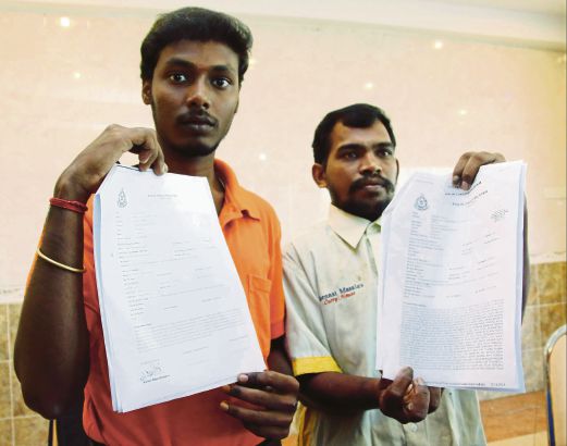 Aravan  (kanan) dan Mohanraj  menunjukkan laporan polis yang dibuat mereka.