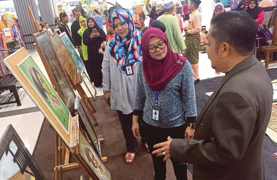 WAN Ahmad (kanan) memberi penerangan kepada pengunjung yang hadir pada pamerannya.